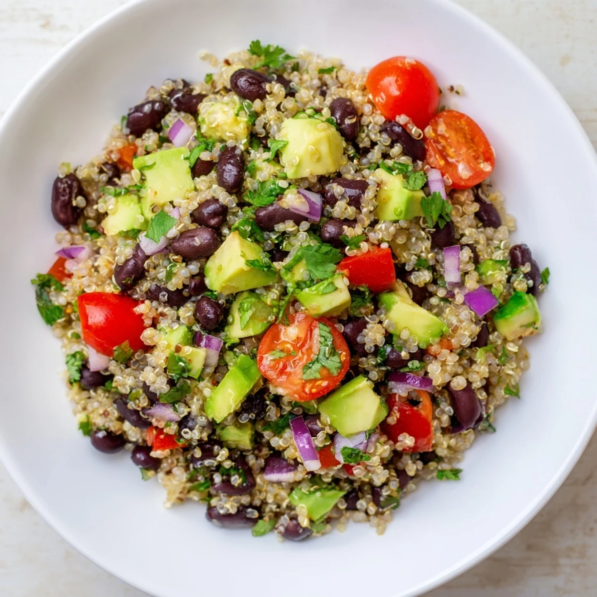 Chilled, zesty Quinoa Black Bean Salad with juicy tomatoes and creamy avocado, perfect for lunch.
