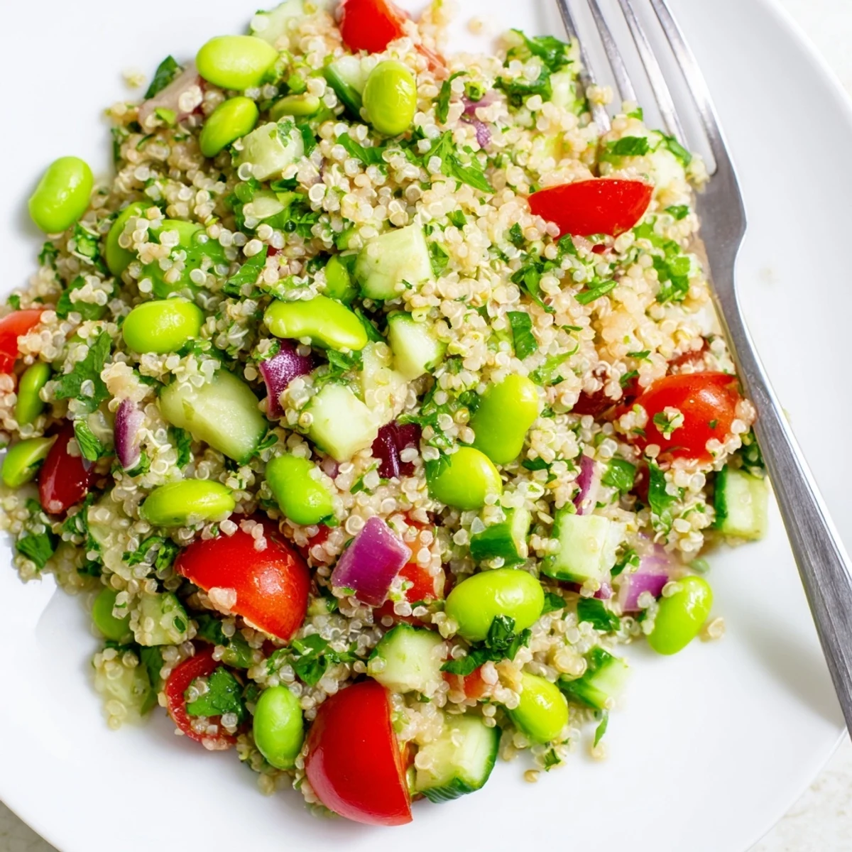 A vibrant serving of Edamame and Quinoa Salad, garnished with parsley and red onion, ready to be enjoyed as a refreshing gluten-free side dish or light dinner.