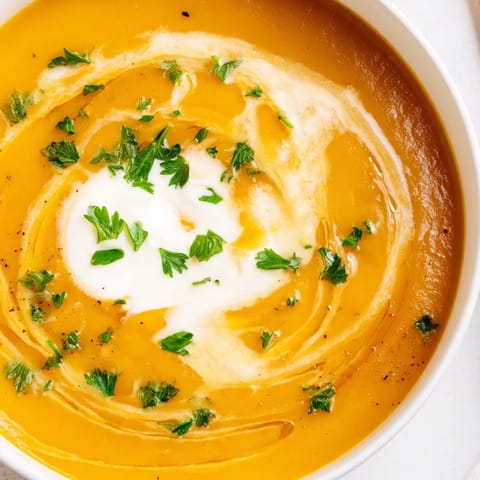 This creamy Sweet Maple Carrot Soup beautifully showcases roasted carrots and sweet potatoes in a bowl.