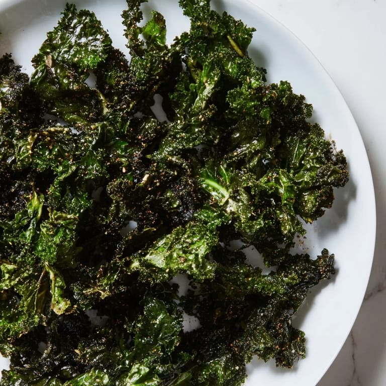 Close-up of baked crispy kale chips, seasoned and ready for a flavorful, crunchy bite.