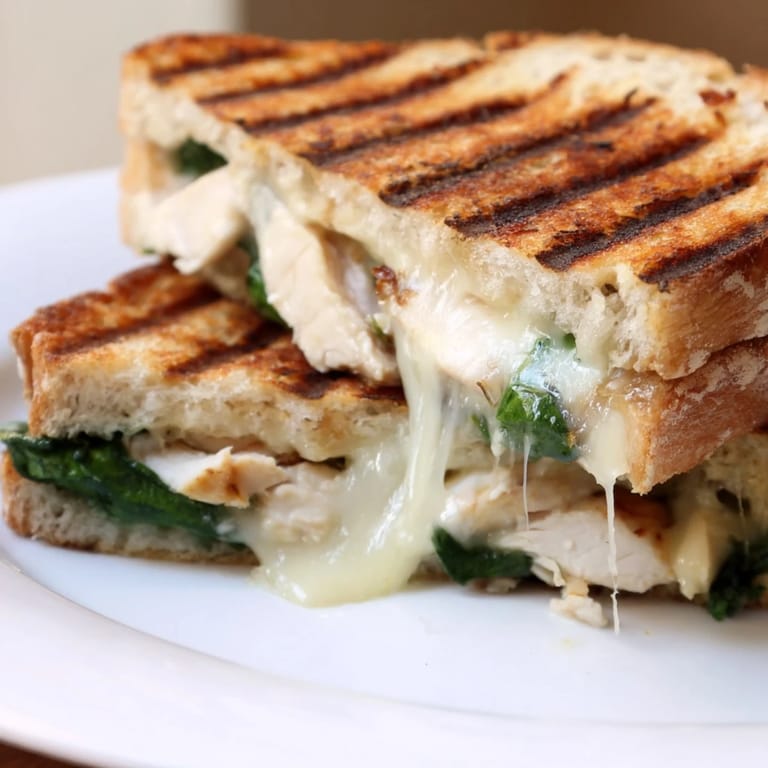 A warm, savory Grilled Chicken Spinach Panini pressed to golden perfection, served hot and gooey.  