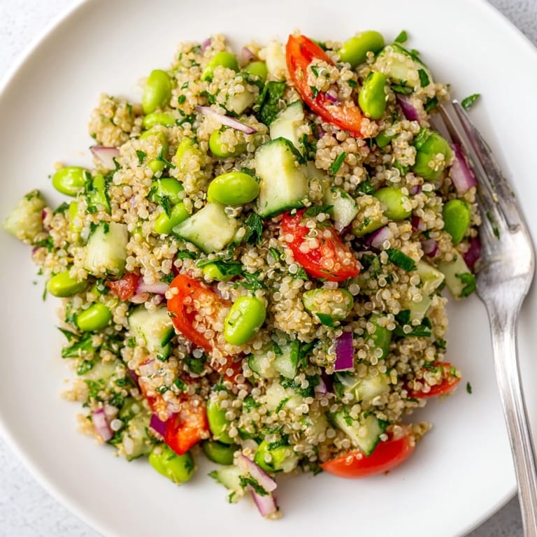 Freshly prepared Edamame and Quinoa Salad in a white bowl, featuring tender green edamame, crisp cucumber, and aromatic mint leaves for a protein-packed, healthy lunch.  