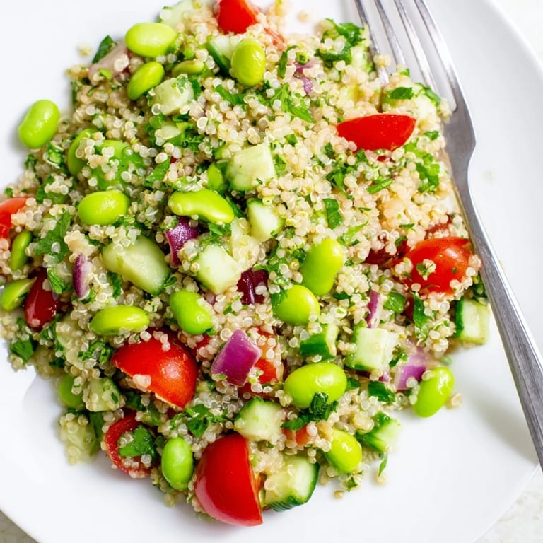 A vibrant serving of Edamame and Quinoa Salad, garnished with parsley and red onion, ready to be enjoyed as a refreshing gluten-free side dish or light dinner.