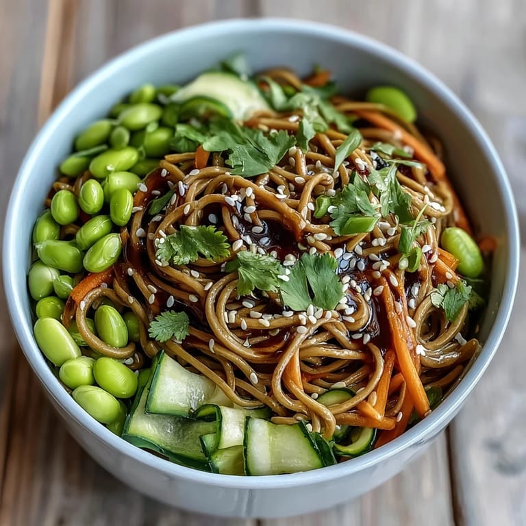 Soba Noodle Bowl served in a white ceramic bowl, garnished with toasted sesame seeds and fresh cilantro, perfect for a vegetarian dinner.  