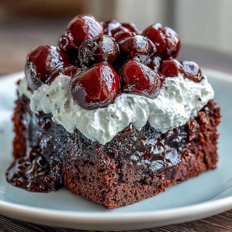 Closeup of rich, layered Cherry Cola Chocolate Poke Cake with whipped cream.